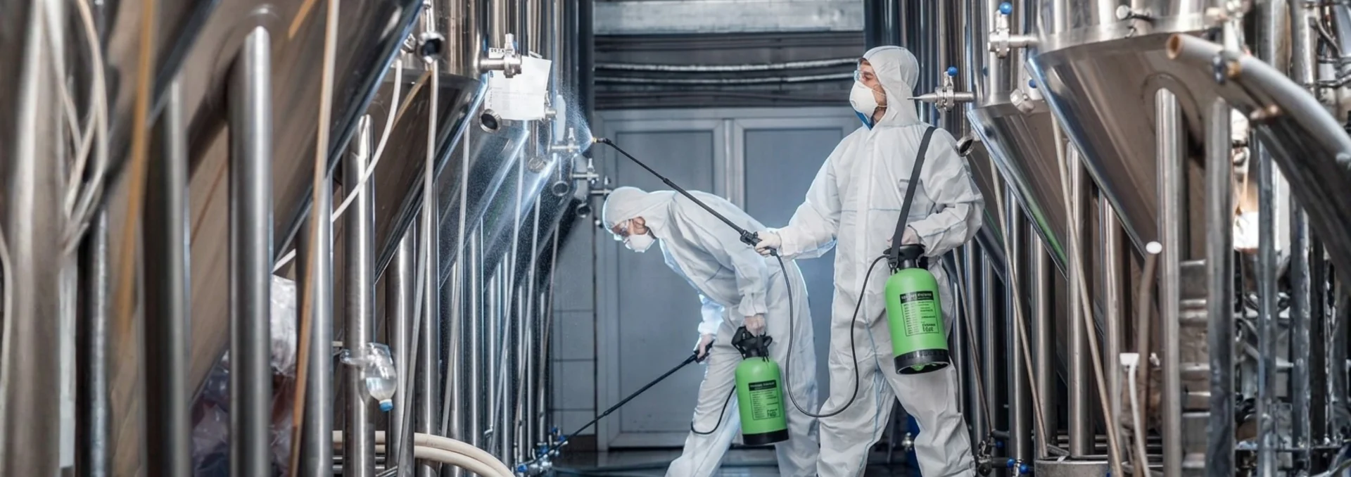 Profissional higienizando tubulações industriais em aço inoxidável.