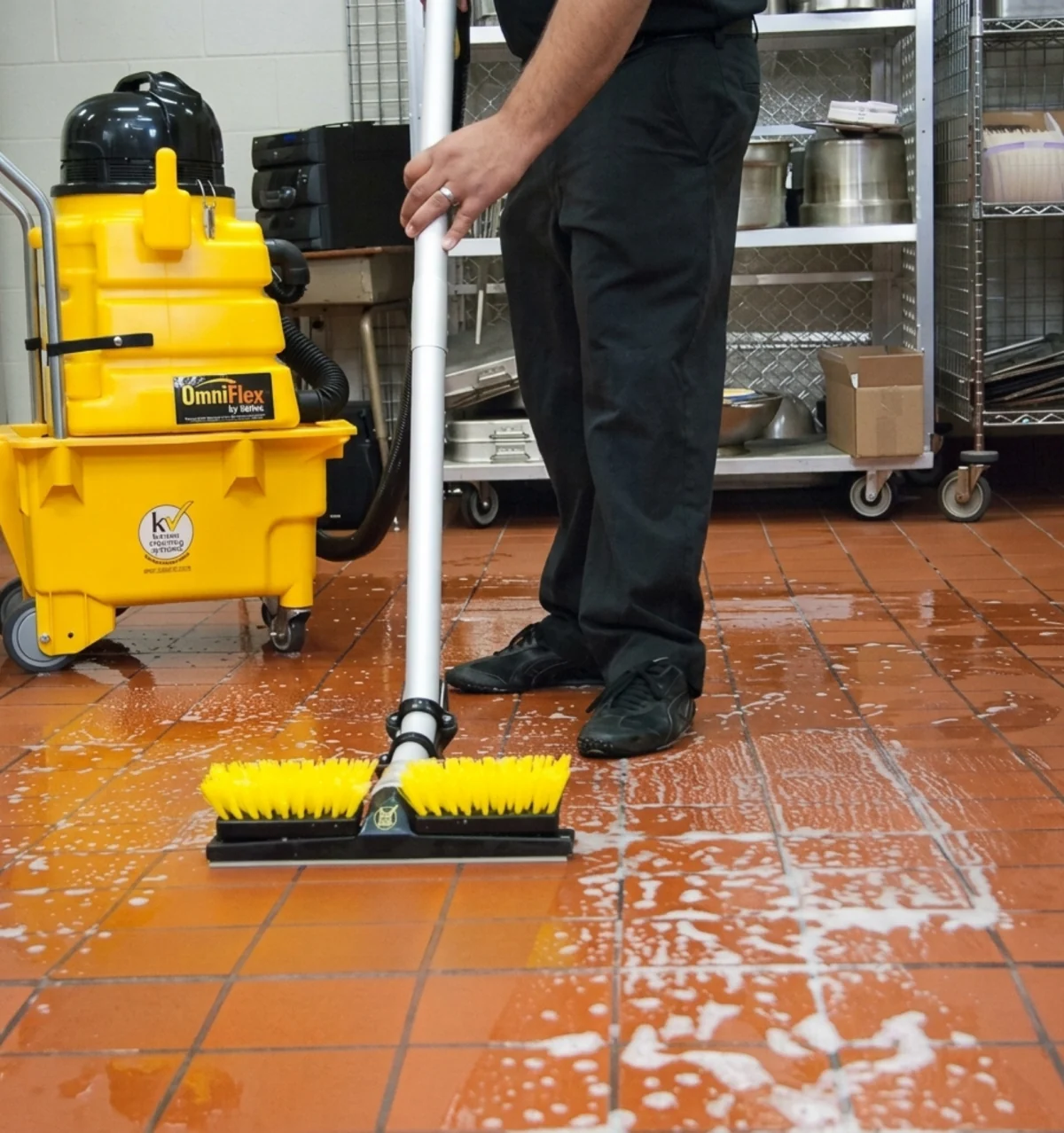 Profissional usando lavadora de piso em área industrial.