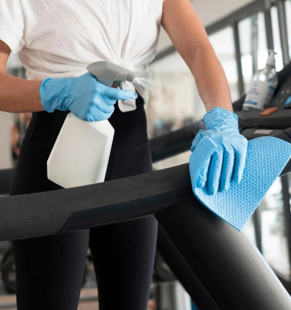 Limpeza de equipamento de academia com pano e produto.