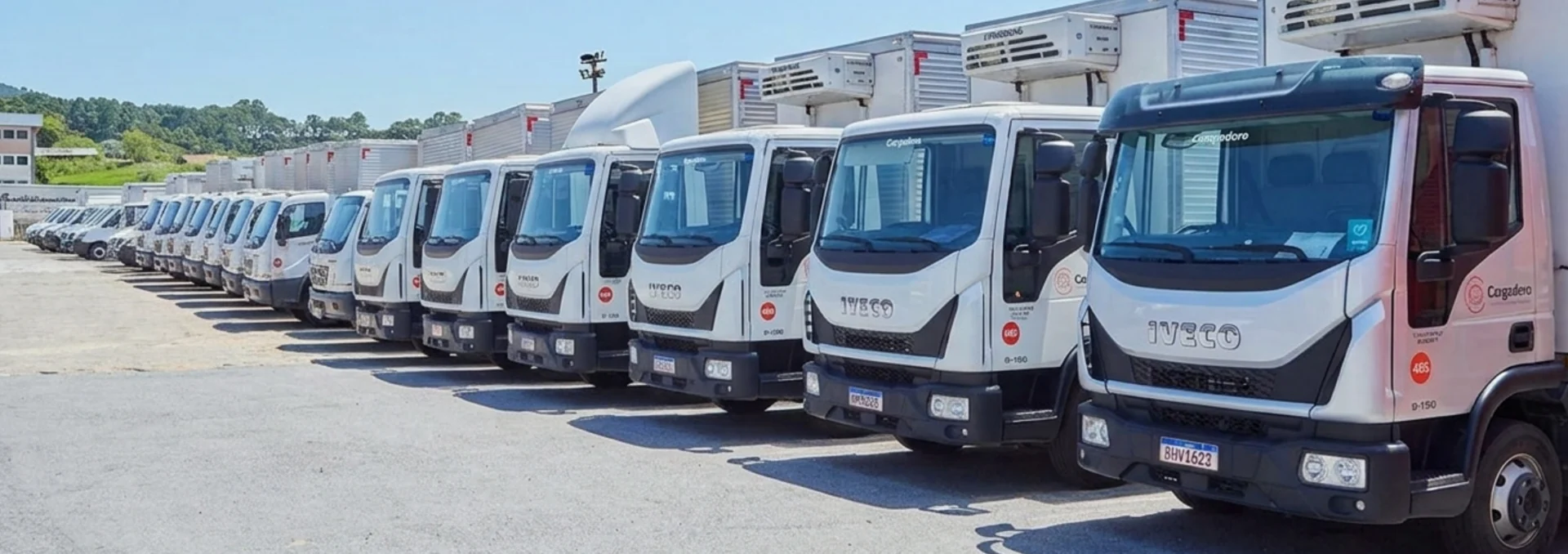 Frota de caminhões estacionada em pátio.