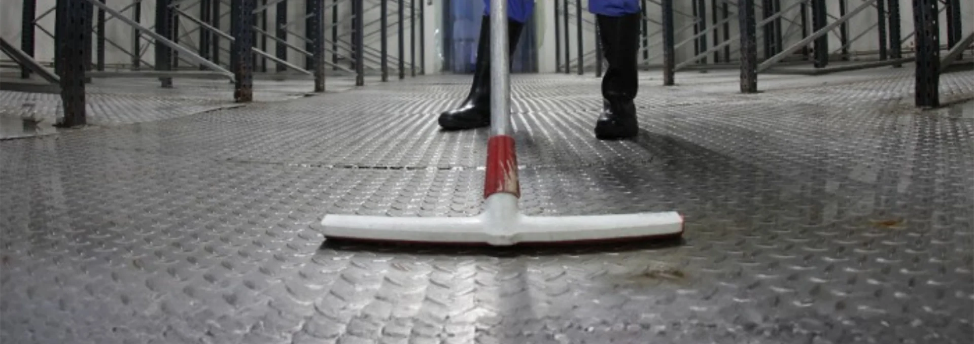 Profissional limpando piso de área industrial.