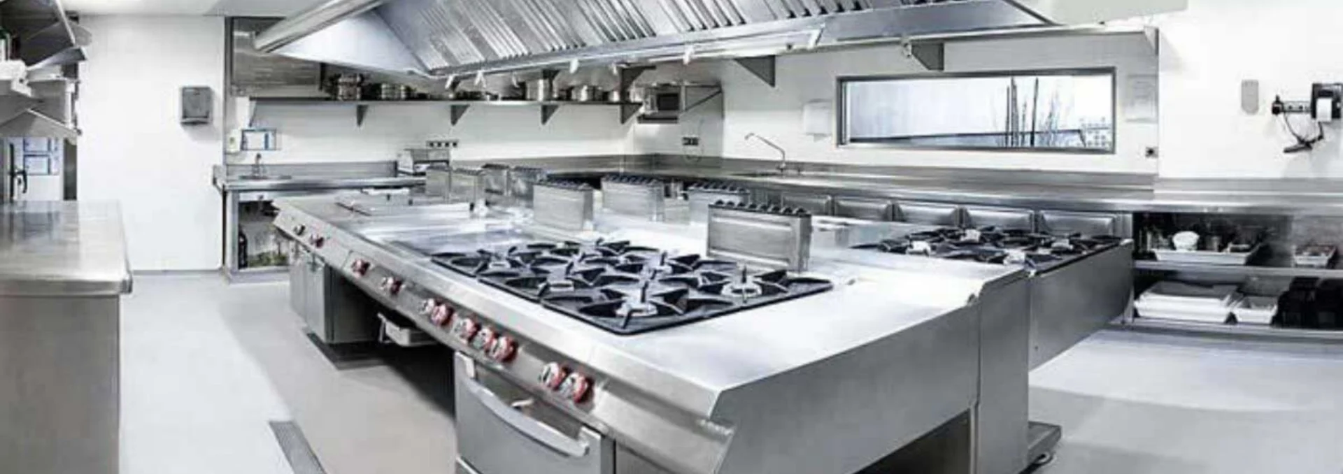 Cozinha profissional com fogão e bancada de aço inoxidável.